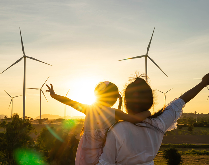 Child and parent in the windmill field and sun shining