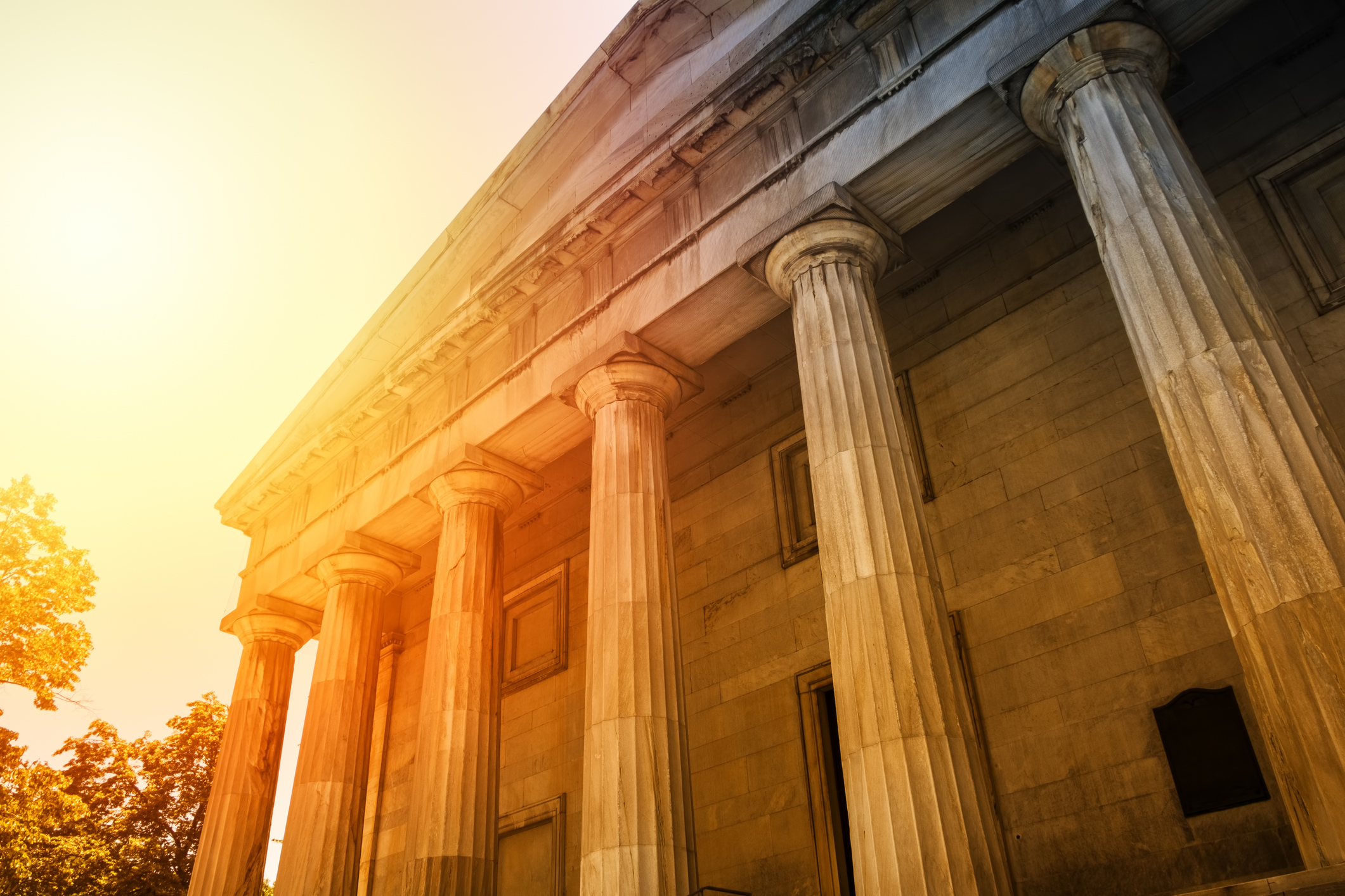 Front of a government building with pillars and sunshine