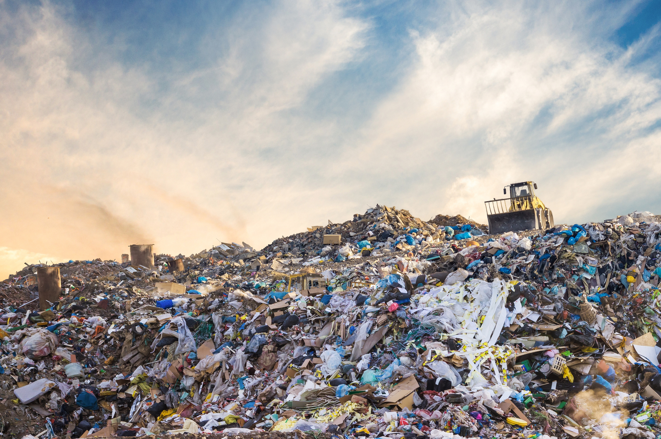 Garbage at the landfill with yellow tracker and smoke